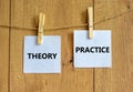 Theory and practice symbol. Wooden clothespins with white sheets of paper. Words `theory practice`. Beautiful wooden background.