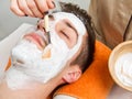 Therapist applying a face mask to a beautiful young man in a spa Royalty Free Stock Photo