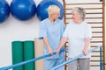 Therapist helping senior woman to walk with parallel bars Royalty Free Stock Photo