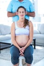 Therapist performing massage on pregnant woman sitting on chair Royalty Free Stock Photo