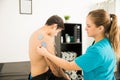 Therapist Placing Electrodes On Man`s Shoulder In Clinic