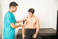 Therapist Placing Kinesiology Tape On Shoulder Of Athlete In Clinic