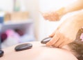 Therapist placing spa hot stone on to a woman back