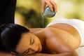 Therapist pouring massage oil on woman`s back.