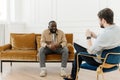 The therapist takes notes while talking to a depressed male patient and talks to an African American patient. Desperate Royalty Free Stock Photo