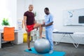 Therapist touching knee of sportsman standing near fit ball