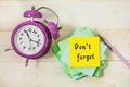 There is an alarm clock on the desktop, a pile of paper for writing. The yellow sticker says - don`t forget Royalty Free Stock Photo