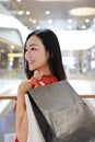 Happy Asian Chinese modern fashionable woman shopping bags in a mall store casual buyer smile laugh consumption on sale promotion
