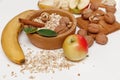 There are Banana,Apple,Orange with Walnuts in the Wooden Plate and Rolled Oats,Wooden Spoon,Trivet,with Green Leaves,Healthy Fresh