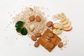 There are Banana,Apple with Walnuts and Rolled Oats,Wooden Trivet,with Green Leaves,Healthy Fresh Organic Food on the White