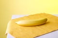 There is a banana on the napkin, the background is yellow