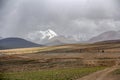 There is a beautiful and spectacular snow mountain in the distance of the dark clouded sky