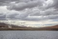 There is a beautiful and spectacular snow mountain under the dark clouds, and there is a light blue lake under the mountain Royalty Free Stock Photo