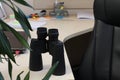 there are black binoculars on the office desk