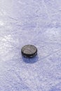 There is black old puck lying on ice of hockey rink, cut by skates. Royalty Free Stock Photo