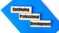 There is a blue notebook on a light gray background. Above are three wooden blocks with the words CPD Continuing Professional Royalty Free Stock Photo