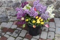 There is a bouquet of colorful lilacs and tulips in a large bucket