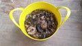 There is a bucket with handles on the wooden floor. In it lamellar black milk mushrooms (LactÃ¡rius nÃ©cator) are soaked in