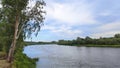 There are bushes and trees on the grassy banks of the river. Further away is the forest. A strong wind creates ripples on the wate Royalty Free Stock Photo