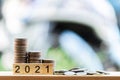 There are coins putting on the wooden table like a growing graph. With text 2021, On green blurry bokeh background. Royalty Free Stock Photo