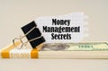 There are dollars on the table, on which there is a clip and torn paper with the inscription - Money Management Secrets Royalty Free Stock Photo