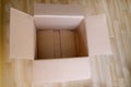 There is an empty open cardboard box on the floor, concept of mailing, package, online shopping, waste paper, renewable product,