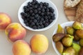 there are figs on the table, bread on a wooden board and blackberries in a plate, as well as ripe peaches.