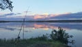 There is a fishing spot on the grassy shore of the lake. A feeder rod with an inertia-free reel is mounted on a fishing stand. Aft