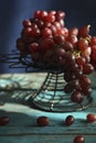 There are fresh grapes on the blue wooden table on the iron flower rack