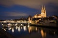Illuminated saint Peter cathedral with historical stone bridge after dark in Regensburg, Bavaria, Germany. Cityscape image over Royalty Free Stock Photo
