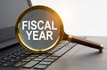 There is a laptop on the table with a magnifying glass that says - FISCAL YEAR