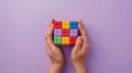 A child\'s hand playing with Lego. There are Legos scattered on the table with a purple background