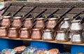 There are a lot of handmade copper dishes on the shelf of a traditional Middle Eastern souvenir shop.