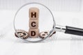 There is a magnifying glass on the documents that points to the cubes with the inscription - HCD Royalty Free Stock Photo