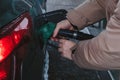 There is a man at a gas station filling up his car with gas