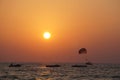 there is a man parasailing on the water with a sun setting in the Royalty Free Stock Photo