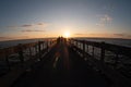 there is a man that is walking along the pier at sunset Royalty Free Stock Photo