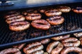 There are many fried sausages on the grill. Cooking food on professional equipment in the restaurant. Close-up Royalty Free Stock Photo