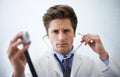 There may be an irregularity...a serious-looking doctor holding up the end of a stethoscope toward the camera. Royalty Free Stock Photo