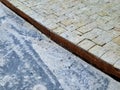 there is a metal sheet curb between the paving. Beige sandstone cube tiles.