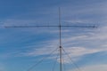 There is a metallic television antenna on the blue sky background