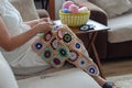 Multicolored plaid squares of crocheted on a cream colored seat and woman is crocheting Royalty Free Stock Photo