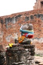 There is no head, Incomplete of ancient stone Buddha and worship by colorful fabric and flower in the ruins and ancient remains.