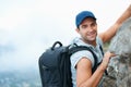 There are no limits for this thrill-seeker. Young climber smiling at the camera as he scales the top of a cliff. Royalty Free Stock Photo