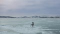 There is an old wooden lonely chair on the ice of a huge lake.