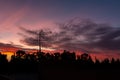 There is a black metallic television antenna and a group of black trees on the beautiful red colorful sunset sky background Royalty Free Stock Photo