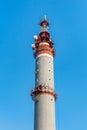 There is one gray and red Radio relay tower with group of different antennas on the blue sky background