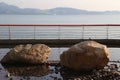 there is an outdoor waterfront park with two large rocks on either side of its edge, surrounded by pebbles in front of them Royalty Free Stock Photo