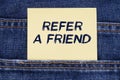 There is a paper sticking out of a jeans pocket with the inscription - Refer A Friend