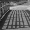 The shadow of the railing makes a pattern on the bridge.